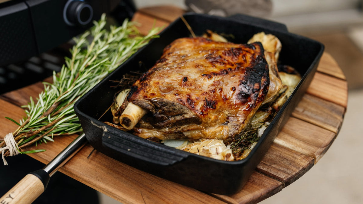 Rosemary Smoked Lamb Shoulder in pan next to a sprig of rosemary