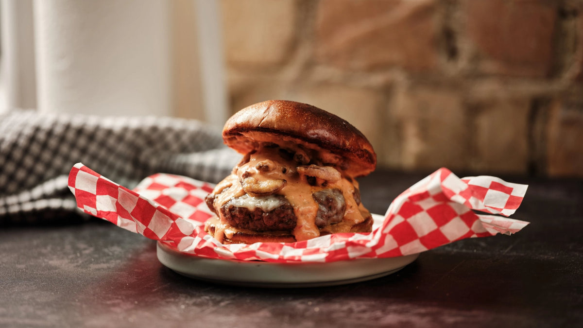 Burger with cheese and mushrooms on a plate with deli paper
